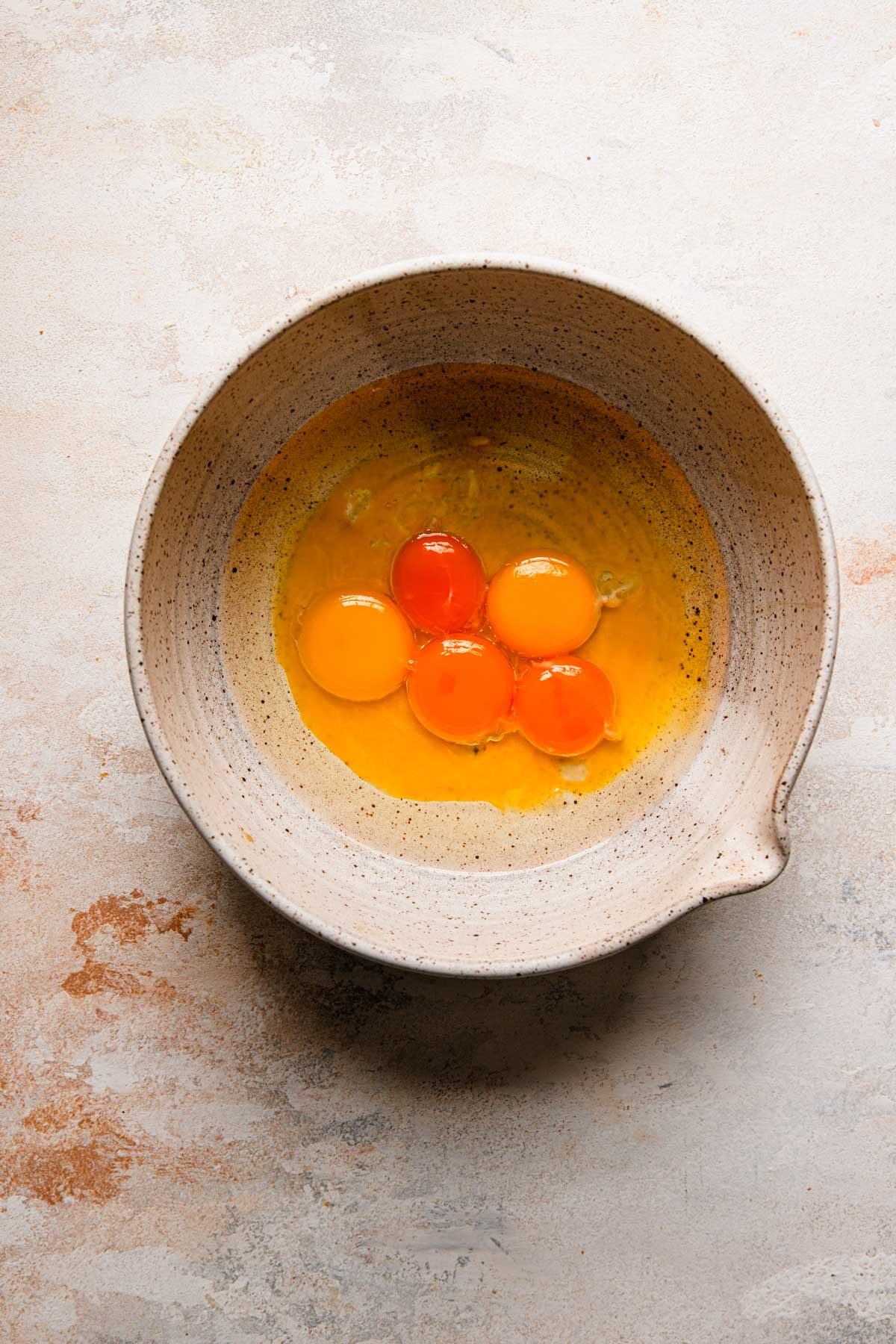 A large bowl with egg yolks and oil.