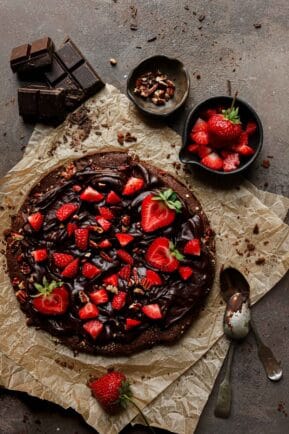 A brownie dessert with ganache and strawberries