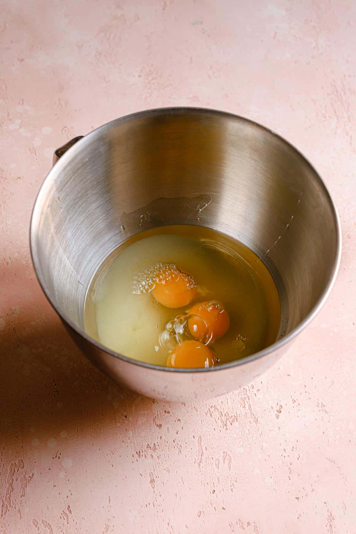 A mixing bowl with eggs, sugar and oil.