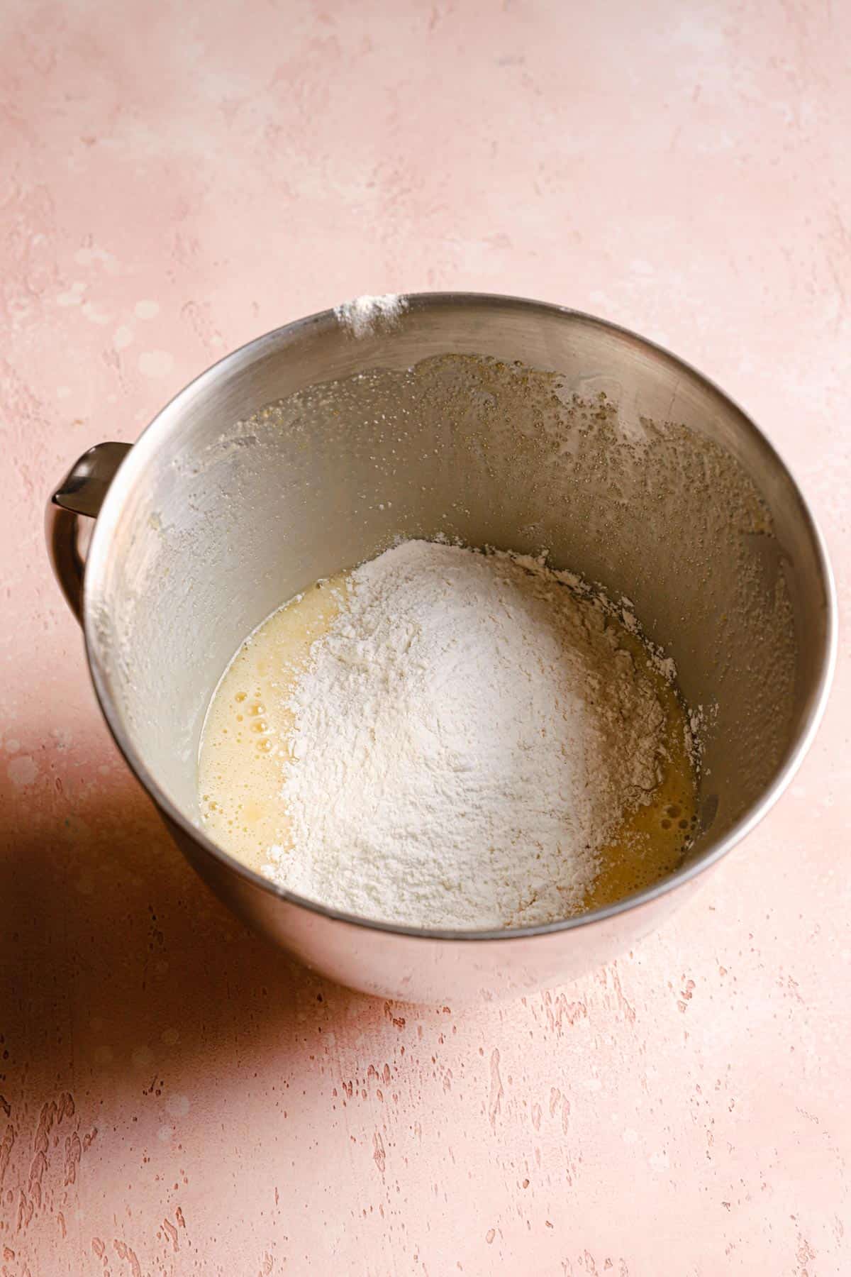 A mixing bowl with flour over eggs mixture.