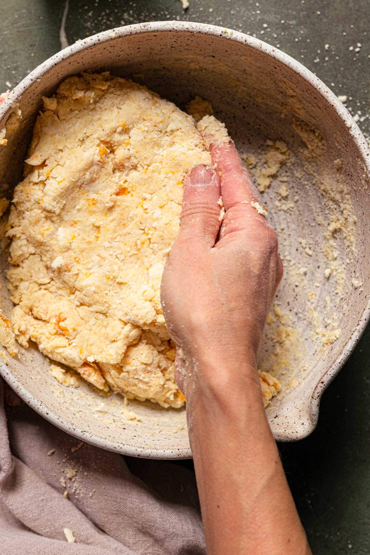 A hand pressing dough in a bowl.