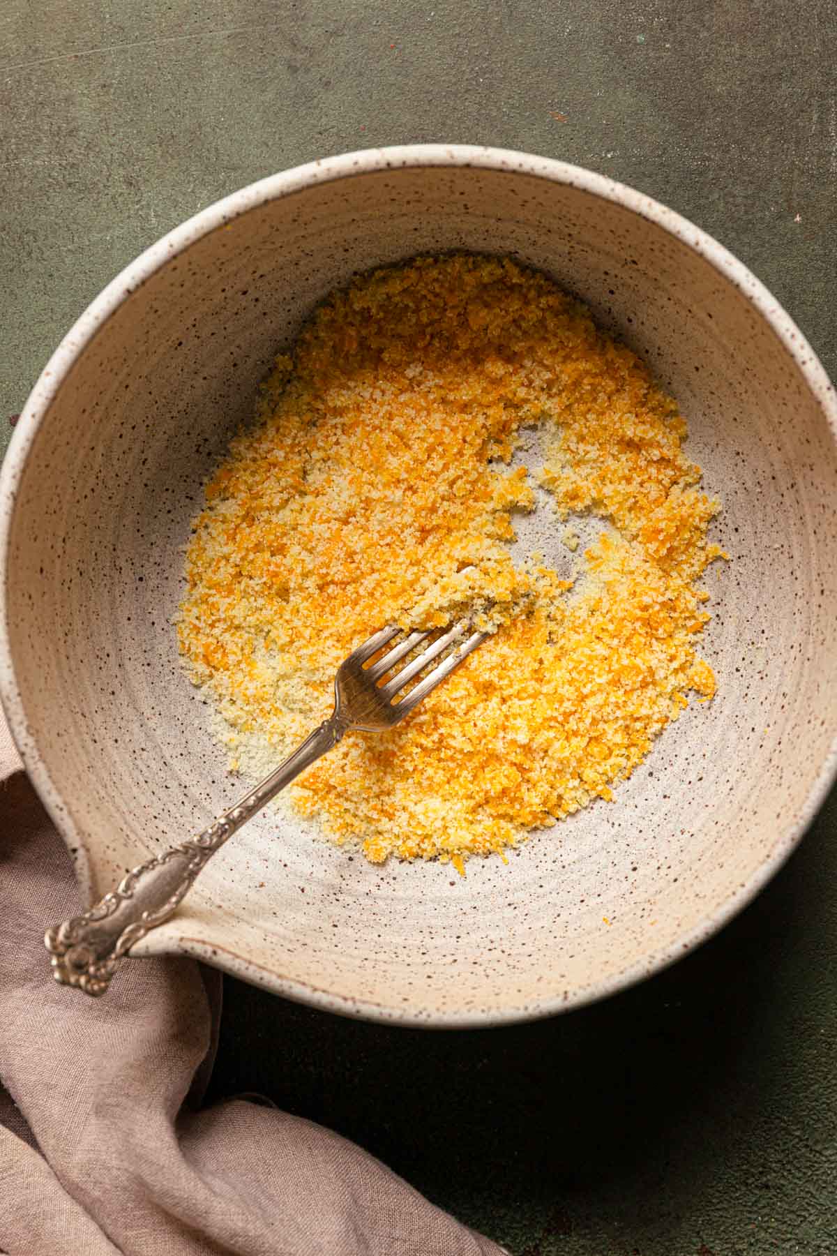 A bowl with sugar and orange zest and a fork.