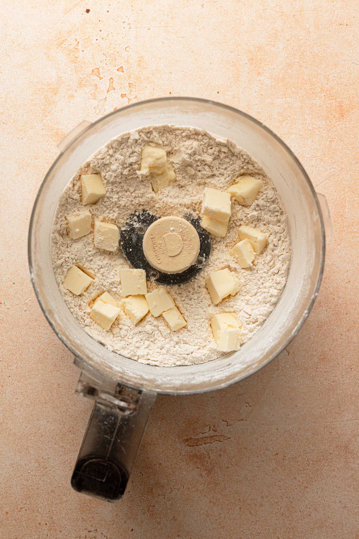 A food processor bowl with flour and butter chunks.