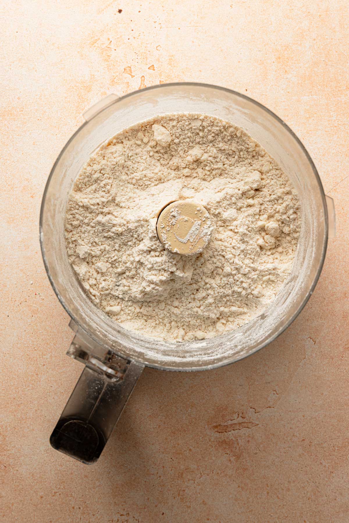A food processor bowl with flour mixture.