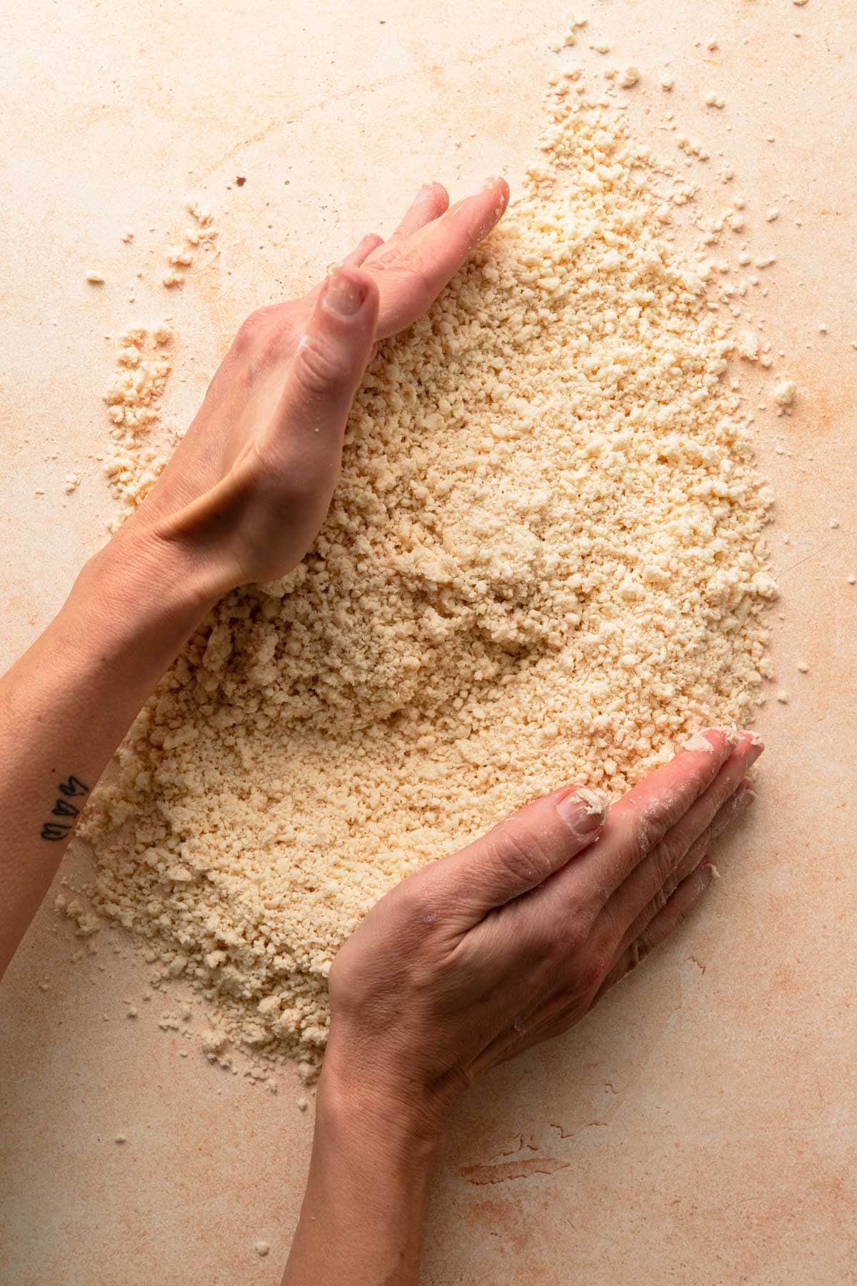 Hands collecting dough crumbs.