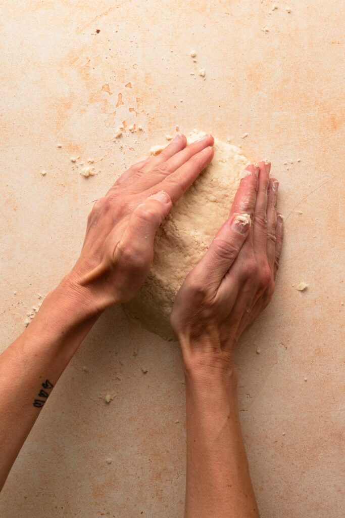 Hands pressing dough.