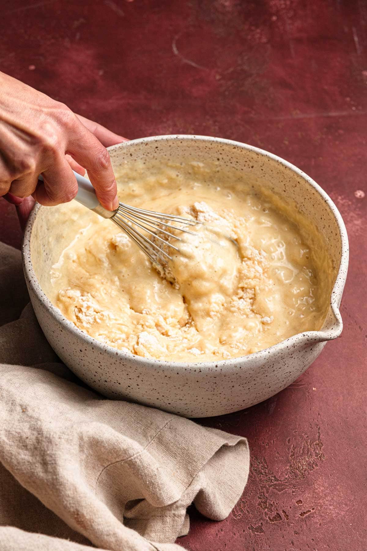 A hand mixing batter with a hand mixer.