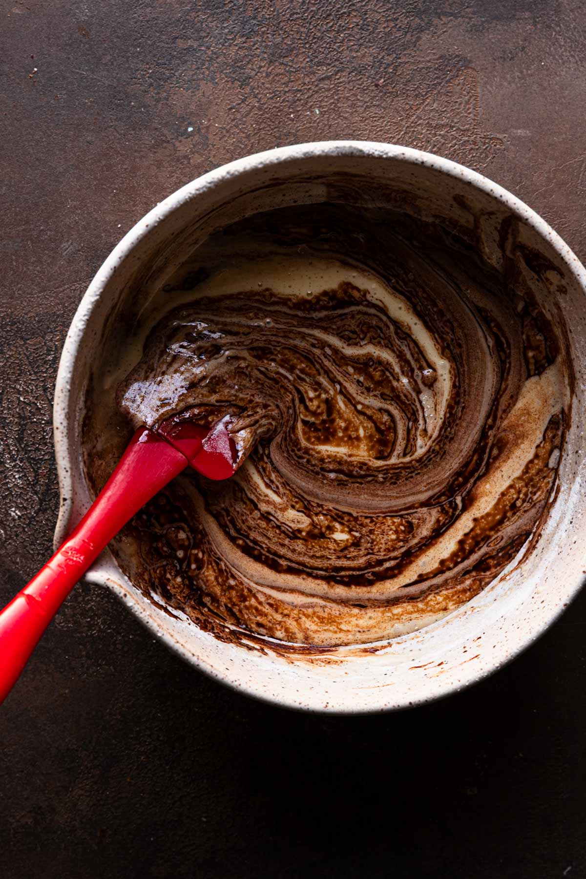 a bowl with egg mixture folding in chocolate spatula.