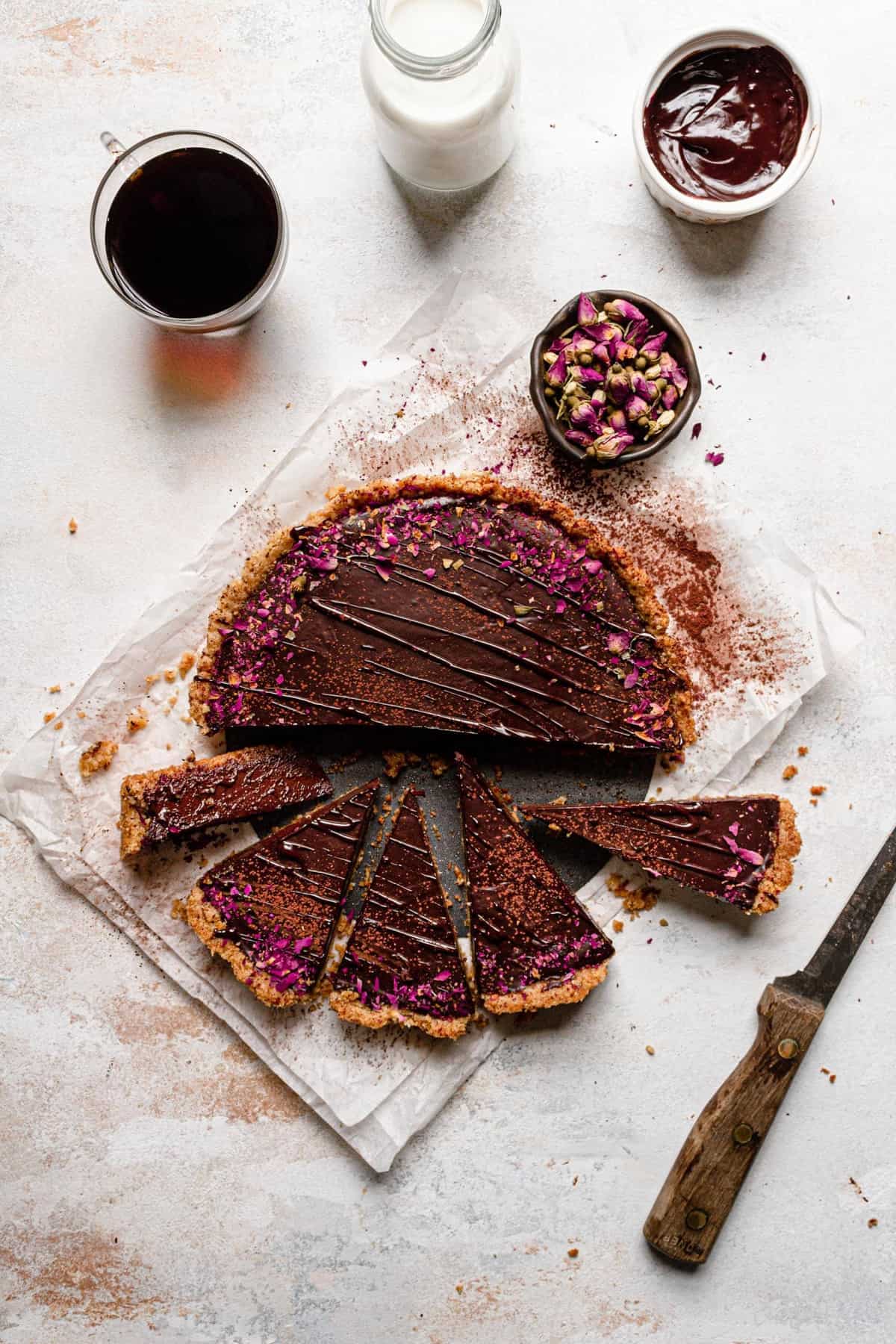 sliced tart decorated with dried flowers a knife next to it