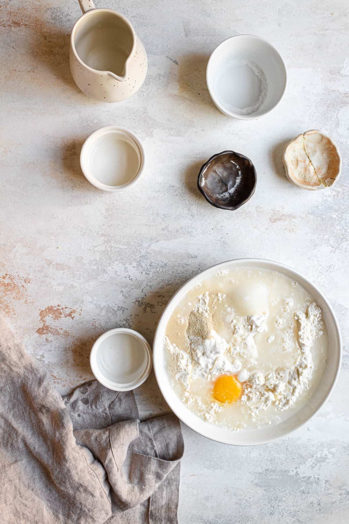 A bowl with flour, sugar, yeast and an egg, water on top.