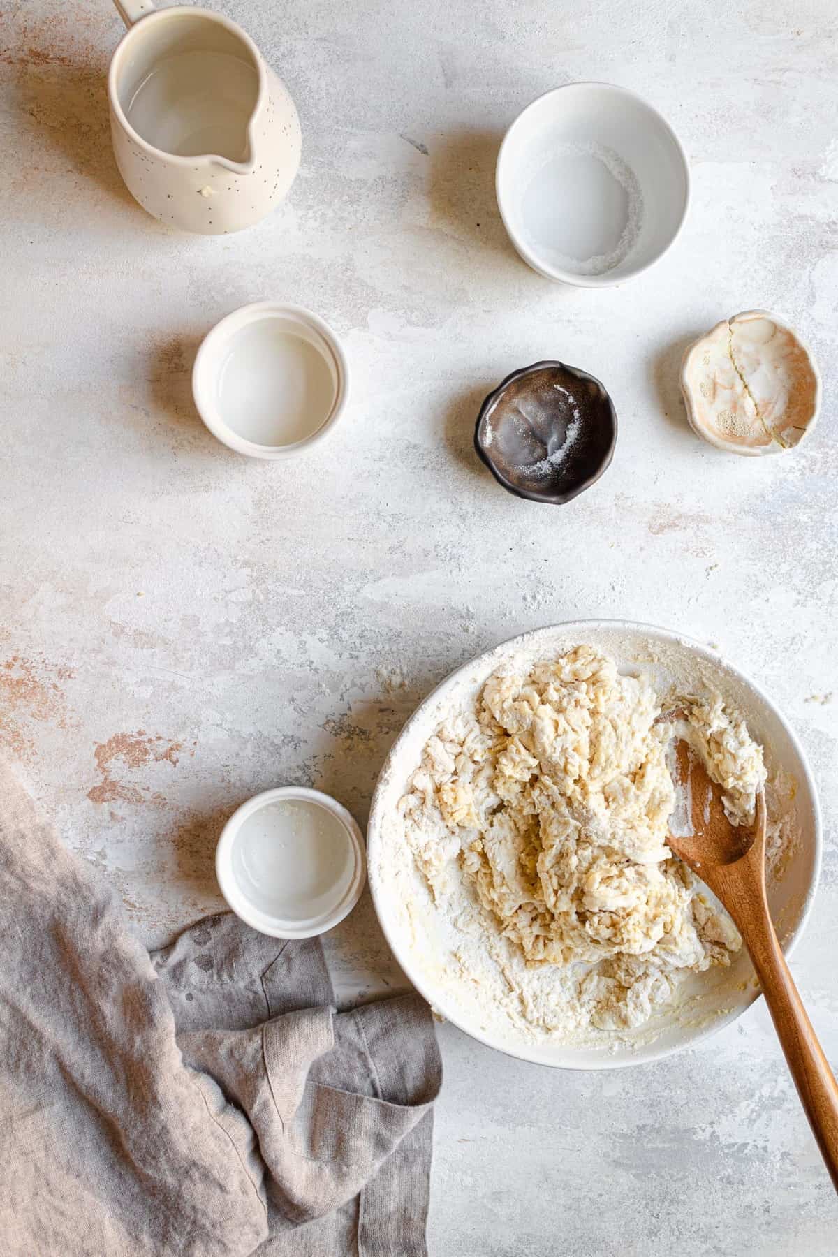 A bowl with a rough dough and a wooden spoon.