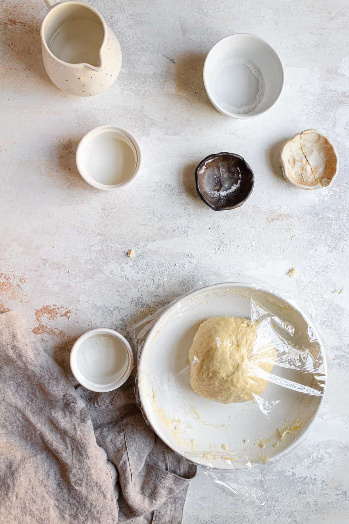 A bowl with dough covered with plastic wrap.