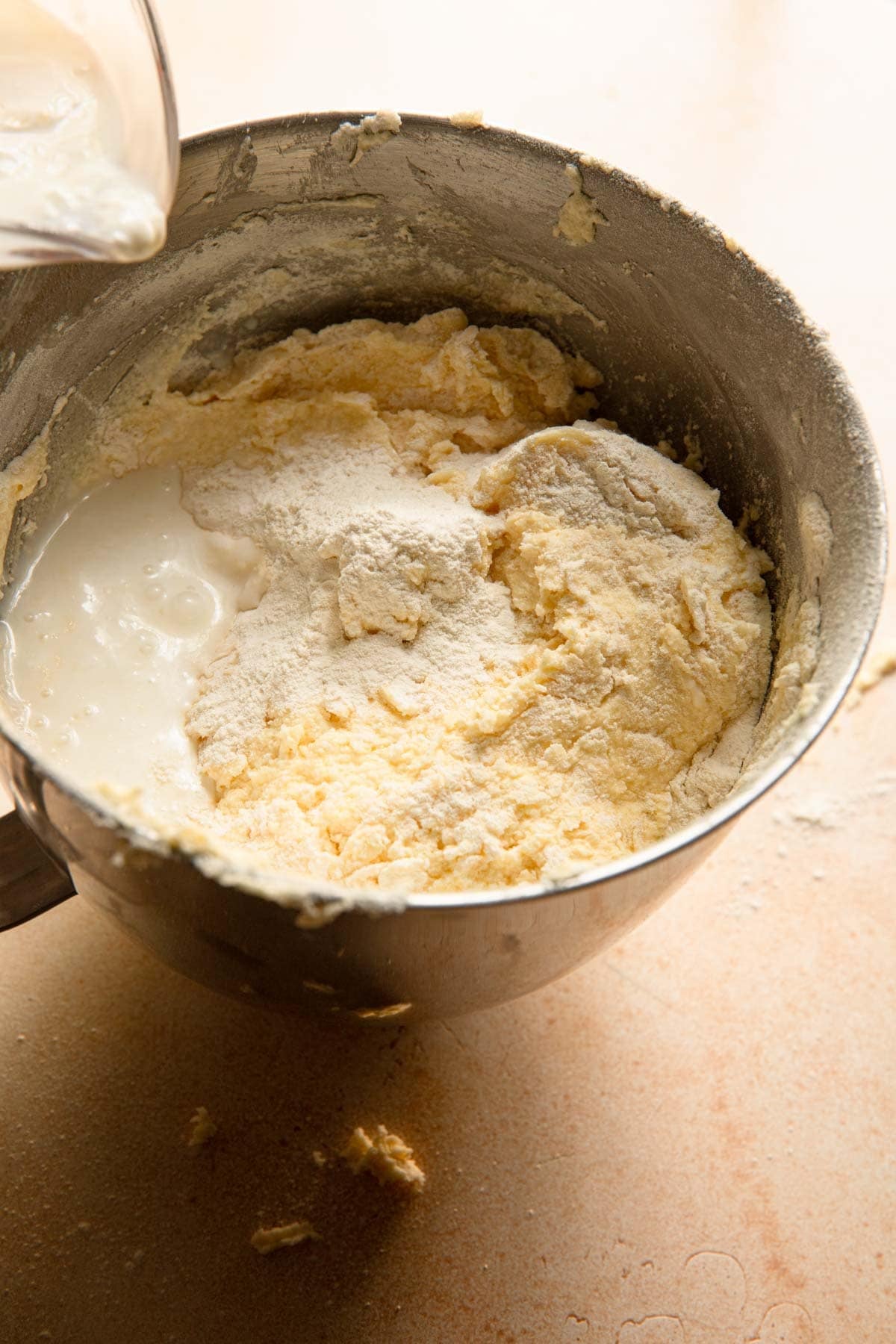 Adding flour and buttermilk to a bowl full of creamed butter and sugar.