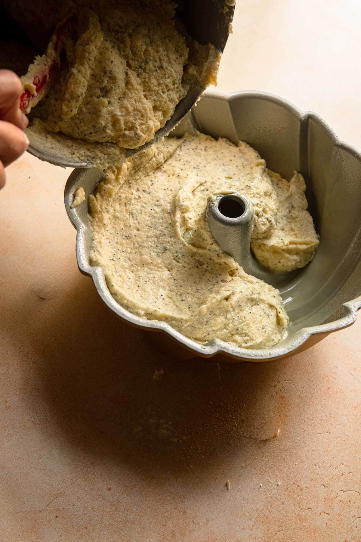 Filling a bundt pan with cake batter.