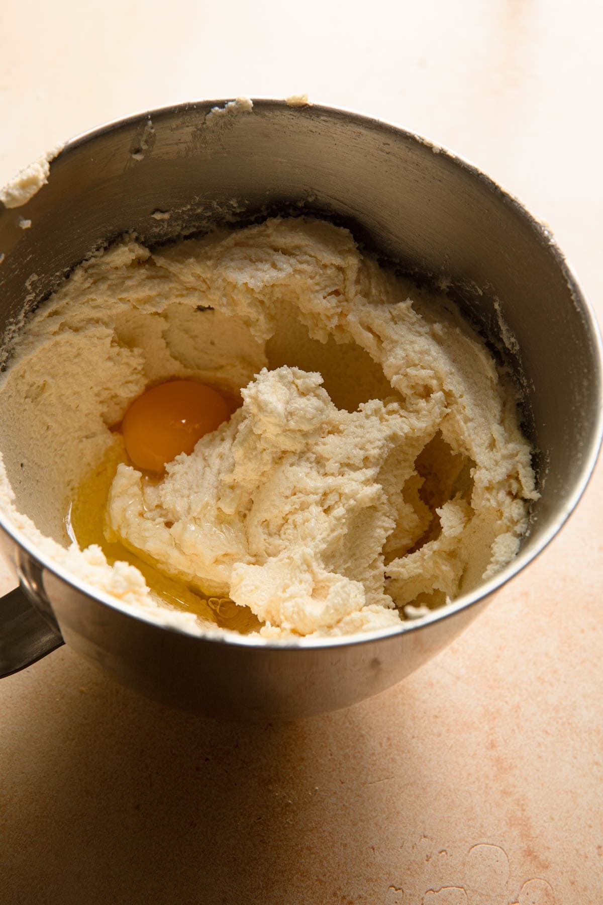 A bowl of a stand mixer with cream butter and sugar and an egg.