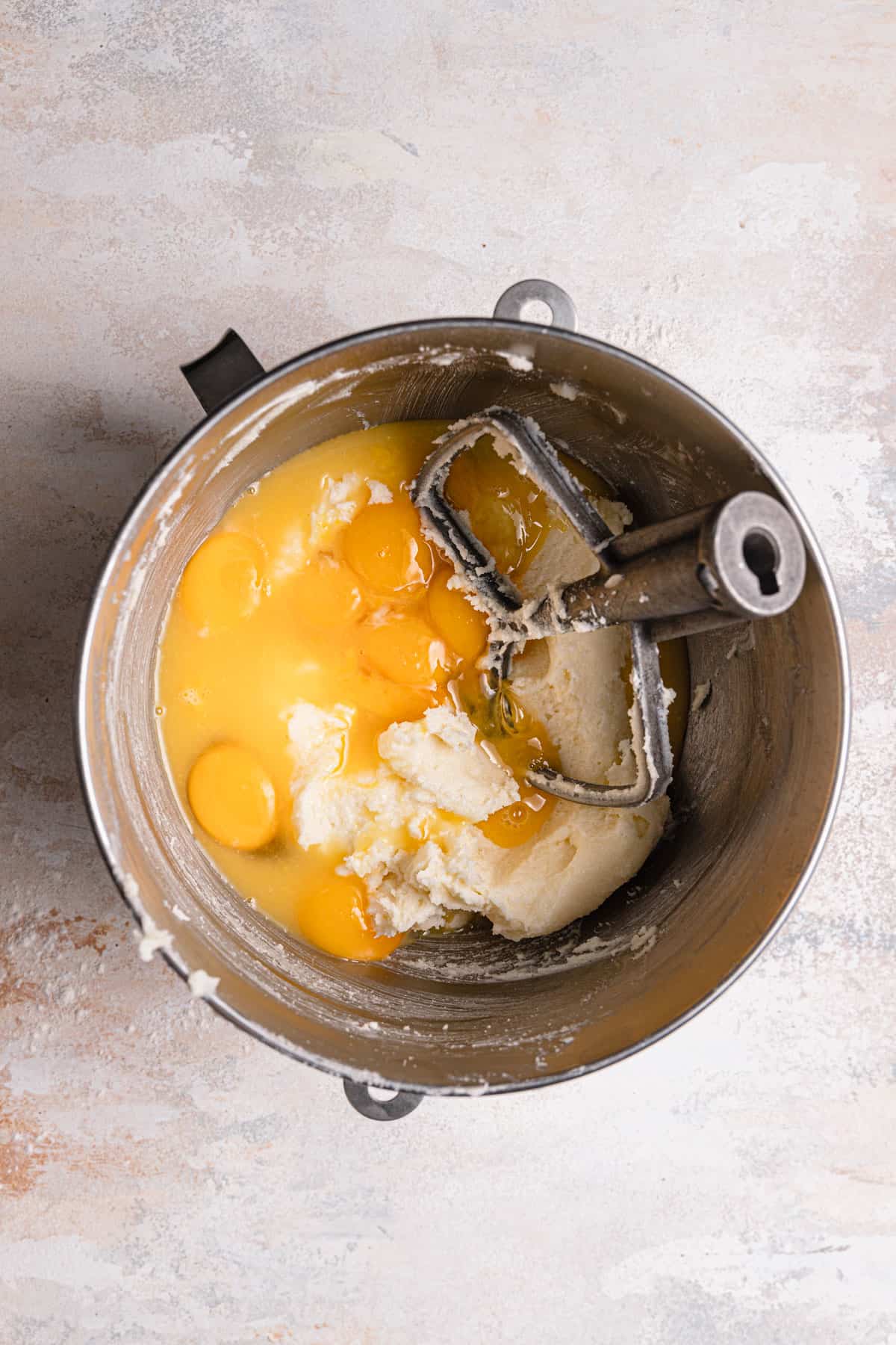 A mixing bowl with creamed butter, and egg, and the paddle attachment.