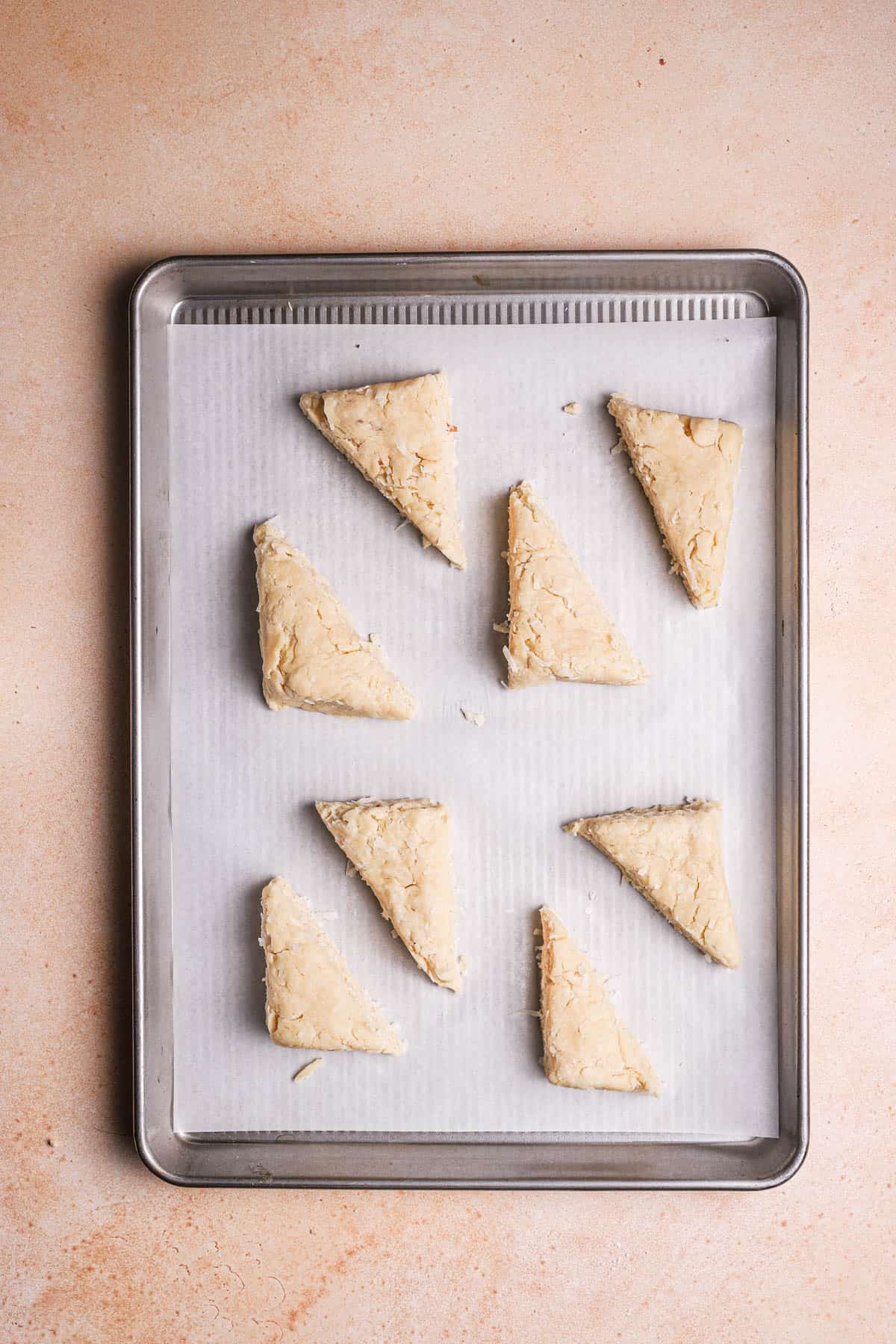 A large cookie pan with eight unbaked scones.