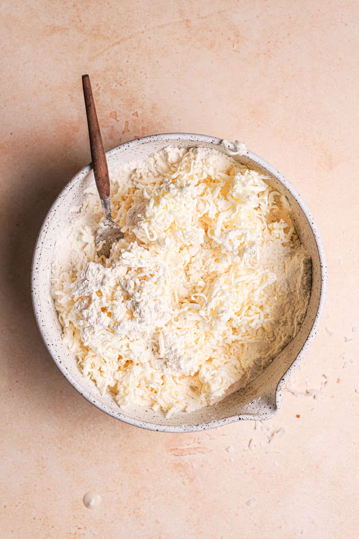 A mixing bowl with flour and shredded butter.