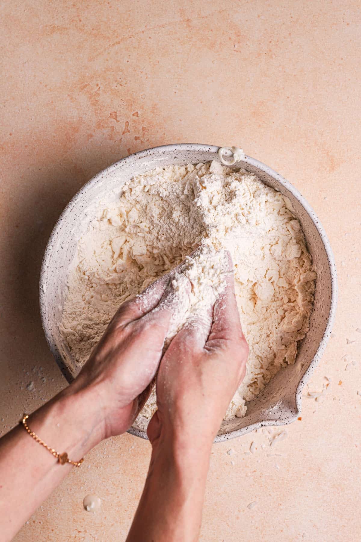 A hand rubbing shredded butter with flour.