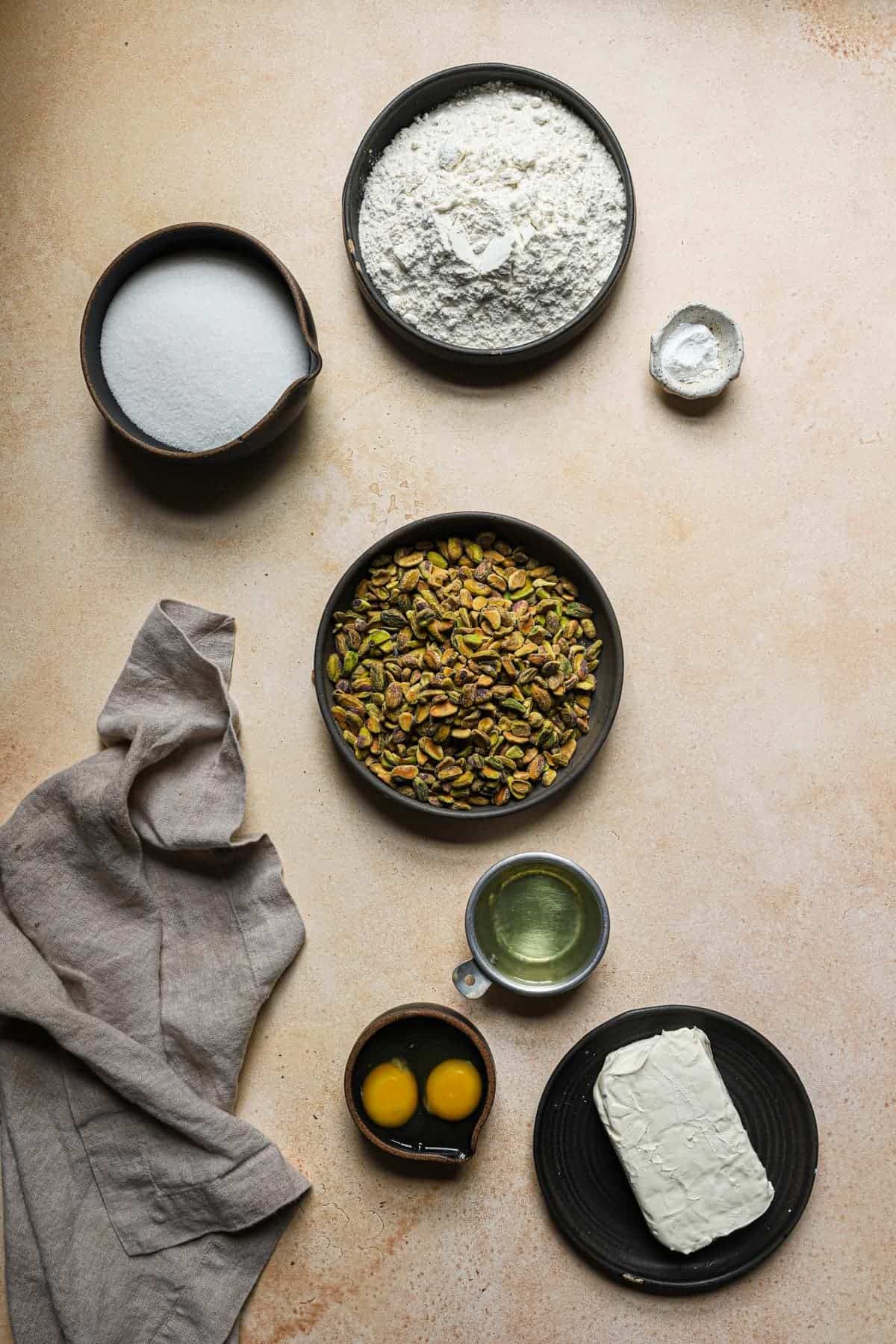 ingredients  in bowls flour, sugar, cream cheese, eggs, oil, pistachios