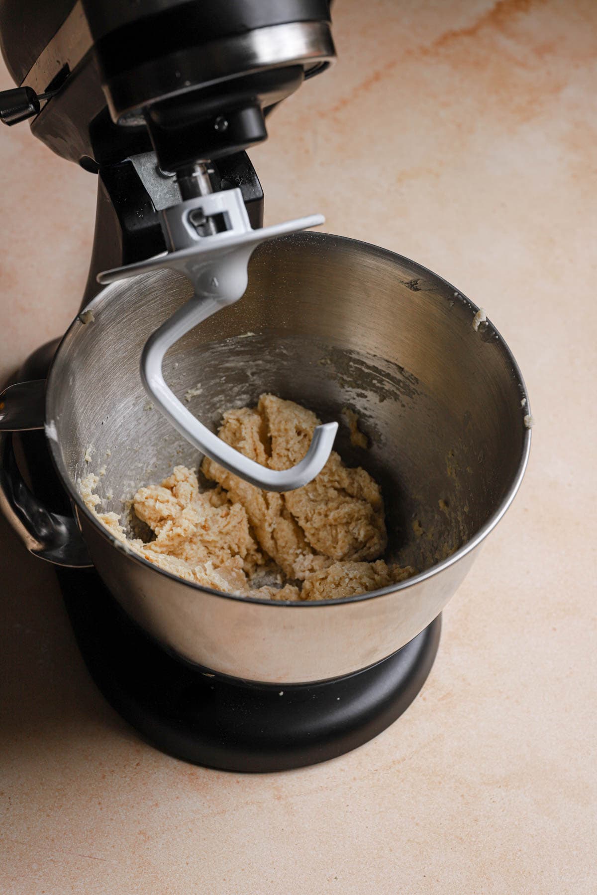 A stand mixer with the dough attachment and dough in the bowl.