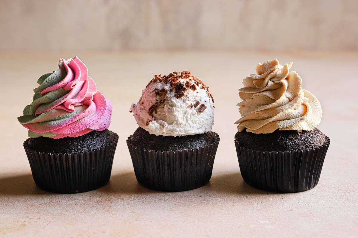 Cupcakes with colored whipped cream, coffee whipped cream and with chocolate shaves.