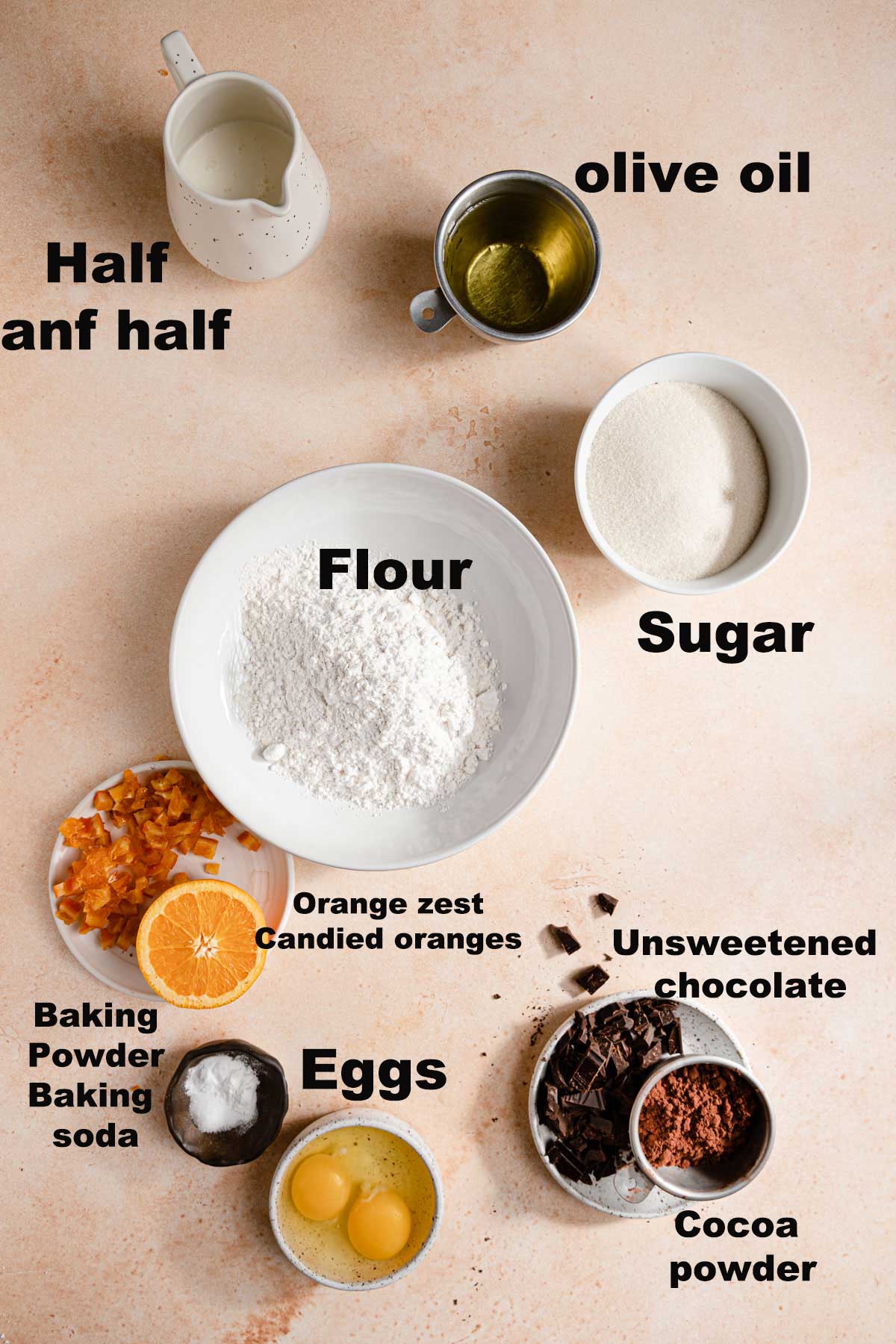 Ingredients in bowls flour, sugar, eggs, baking powder and baking soda, cocoa powder, unsweetened chocolate, olive oil, half and half