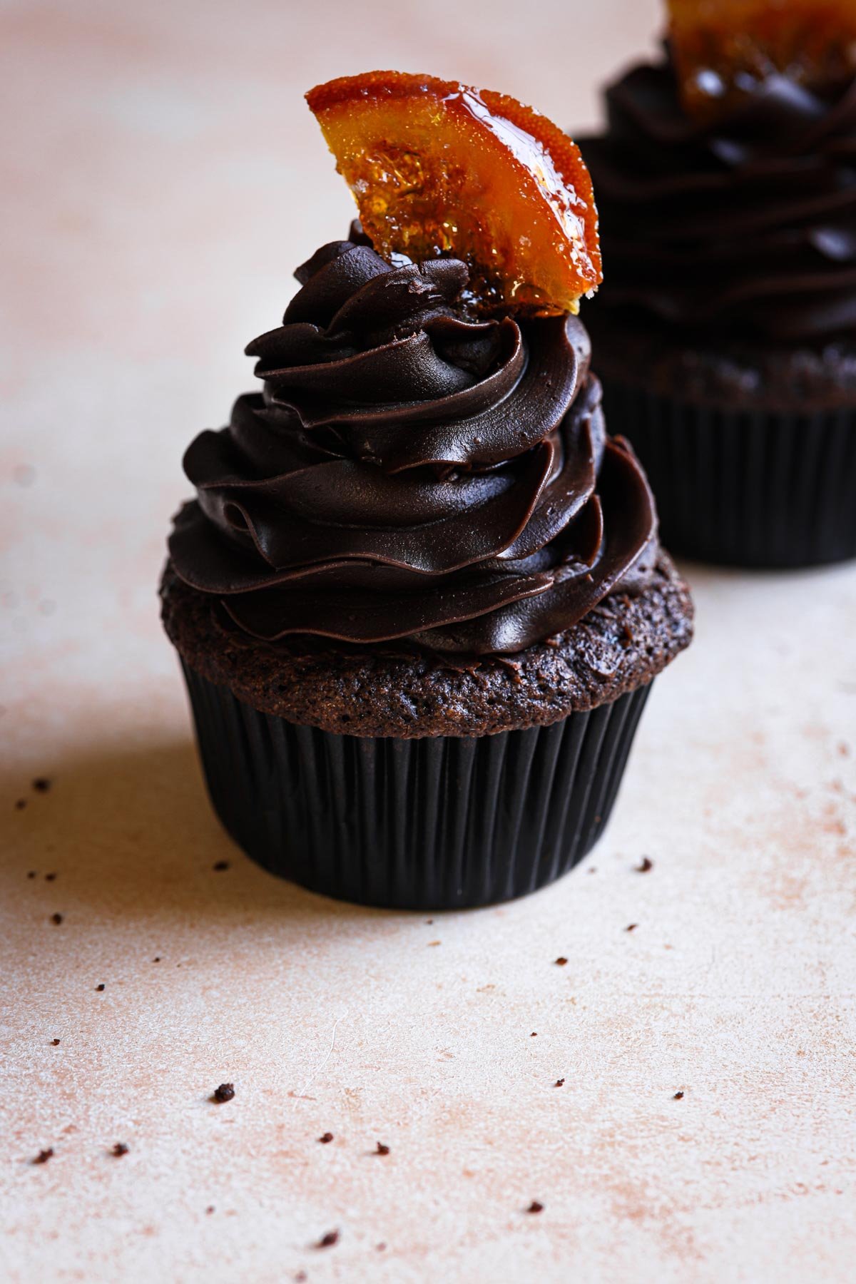 A chocolate orange cupcake topped with chocolate ganache and a slice of candied orange.