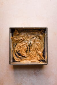 A pan with a layer of brownies and blondie batter on top