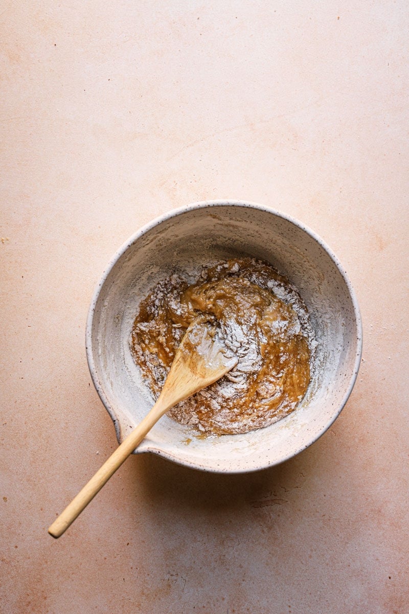 A bowl with blondie batter and a wooden spoon.