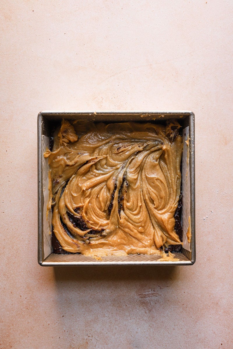 An 8x8 square pan layered swirled brownie and blondie batter.