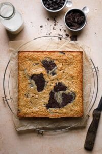 Brownie blondie before cut ontop of a parchment paper and a cooling rack.