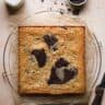 Brownie blondie before cut ontop of a parchment paper and a cooling rack.