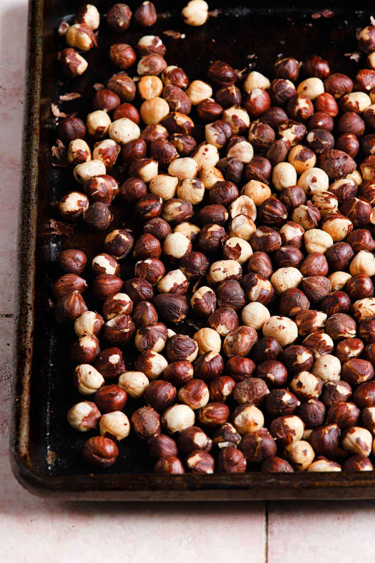 Roasted hazelnuts in a rimmed baking sheet