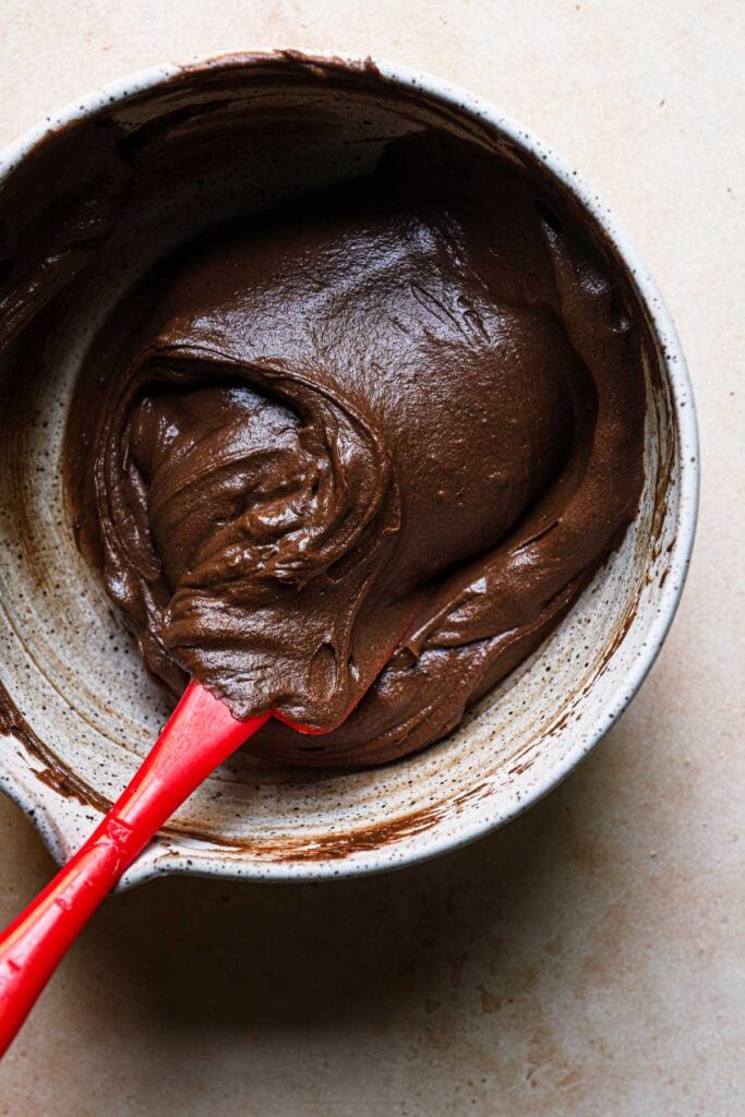 A bowl with brownie cake batter and a spatula.