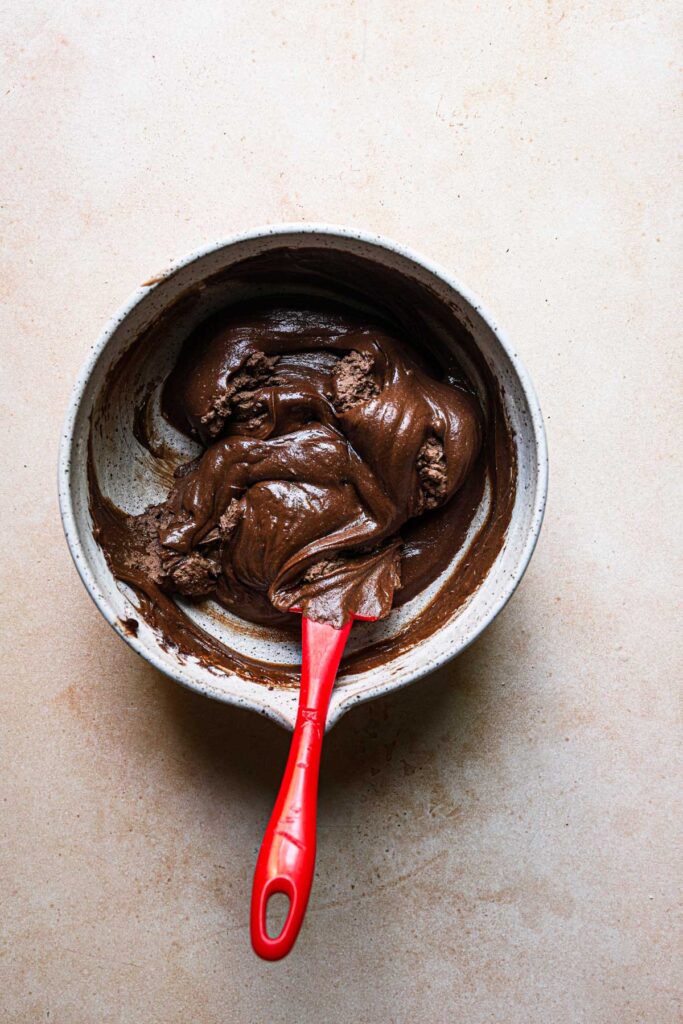 A bowl with a spatula folding cream into batter.