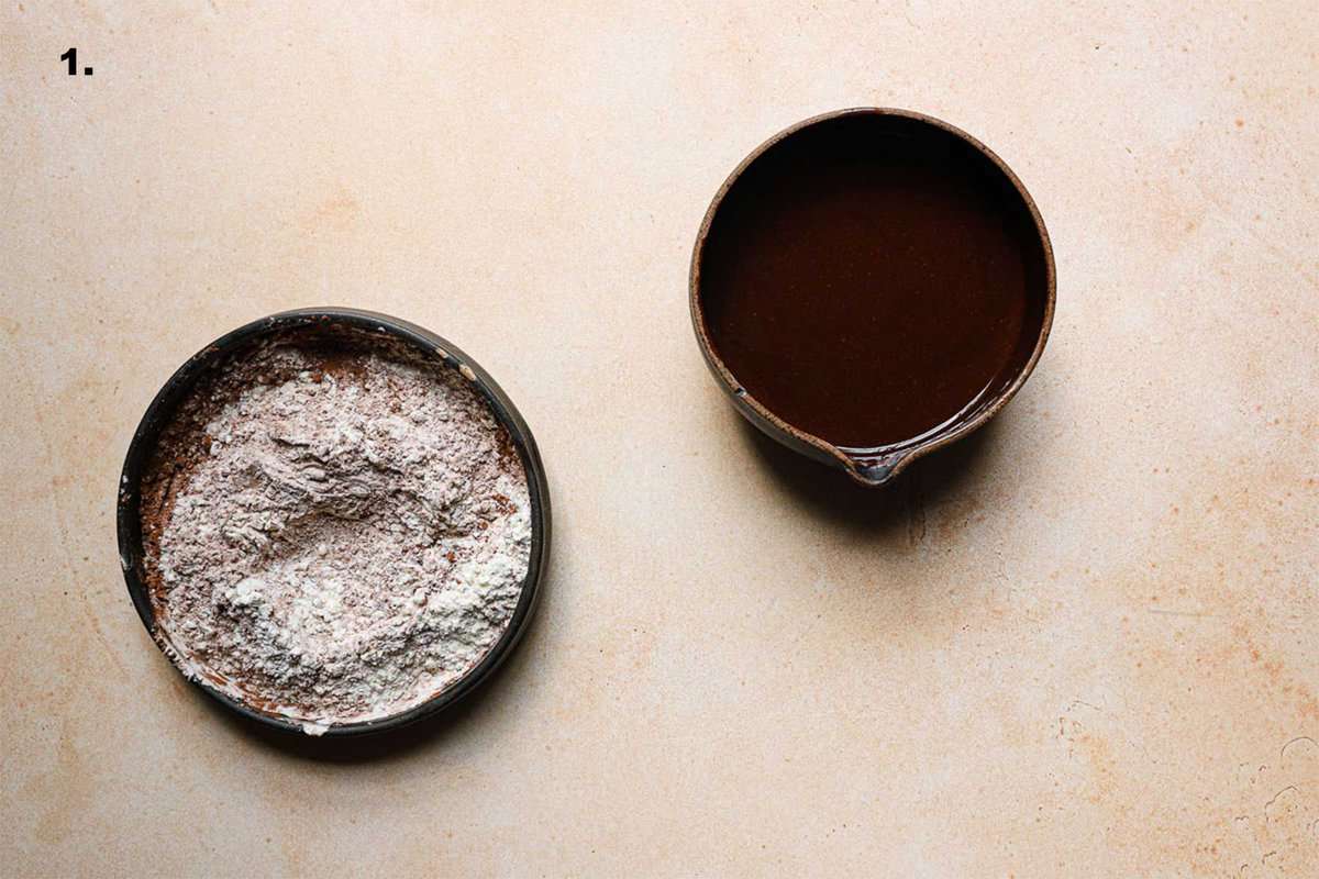 A bowl with flour and cocoa powder and a bowl with melted chocolate.