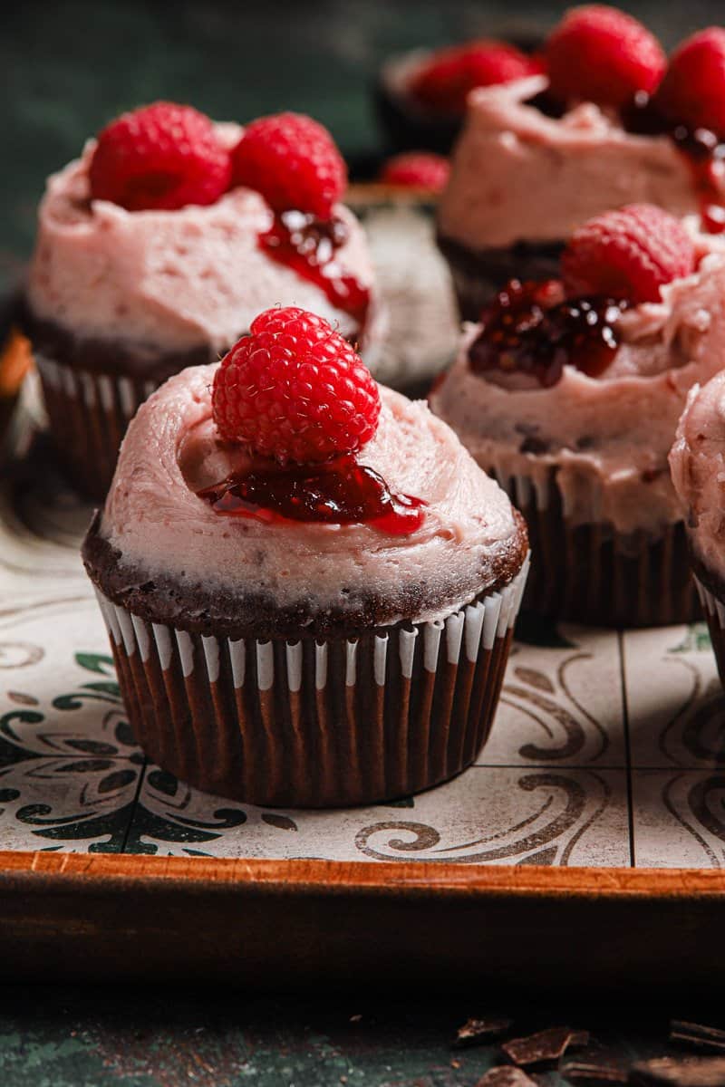 Cupcake frosted with raspberry buttercream and topped with fresh raspberry