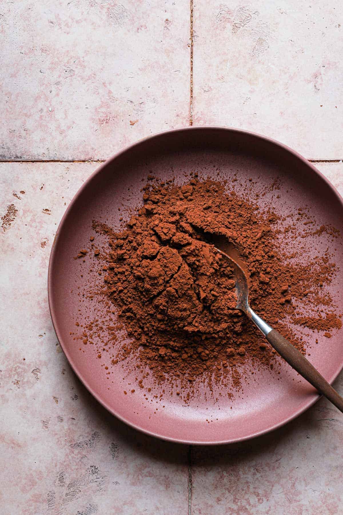A bowl full of natural cocoa powder and a spoon.