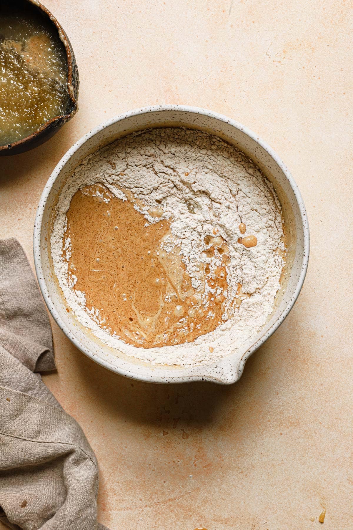 A bowl with cake batter, dry flour and apple sauce.
