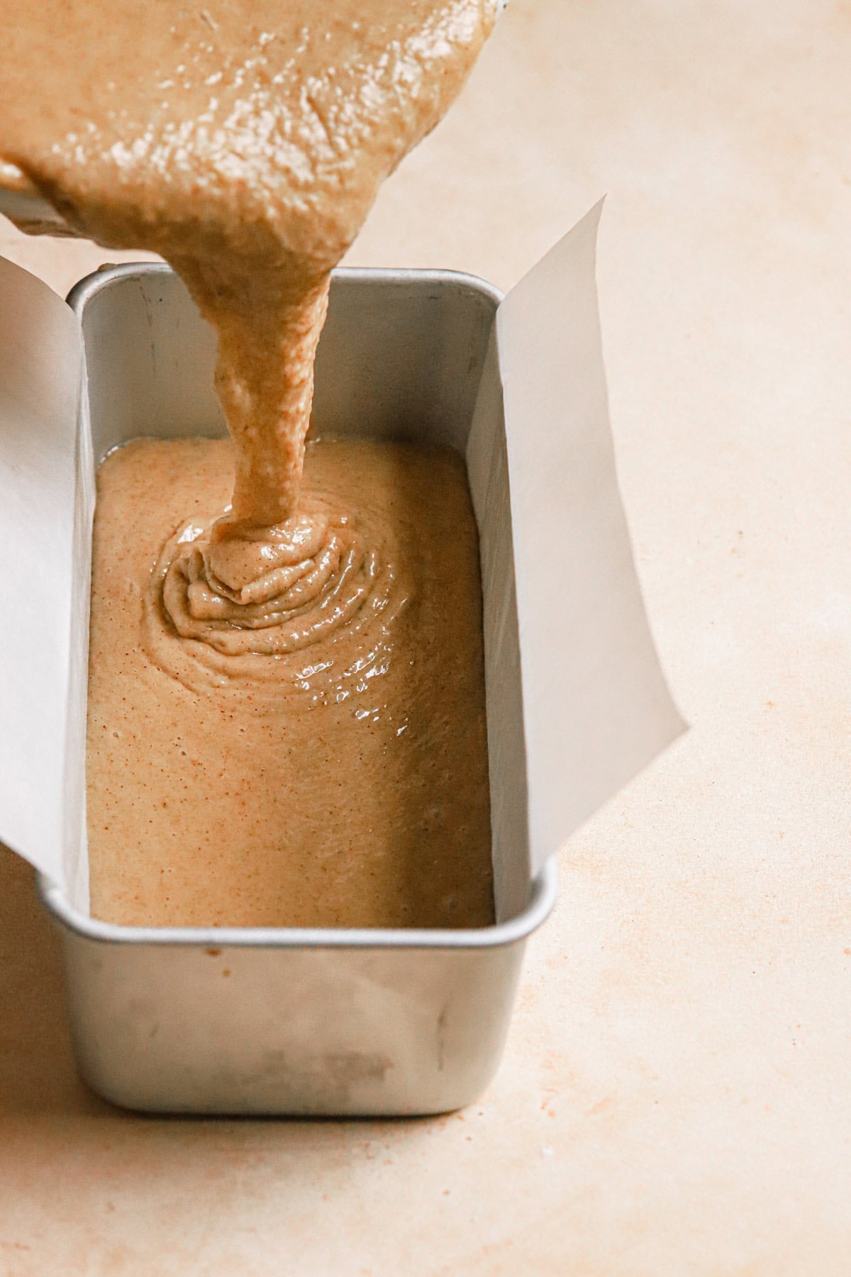 Pouring cake batter into a loaf pan.