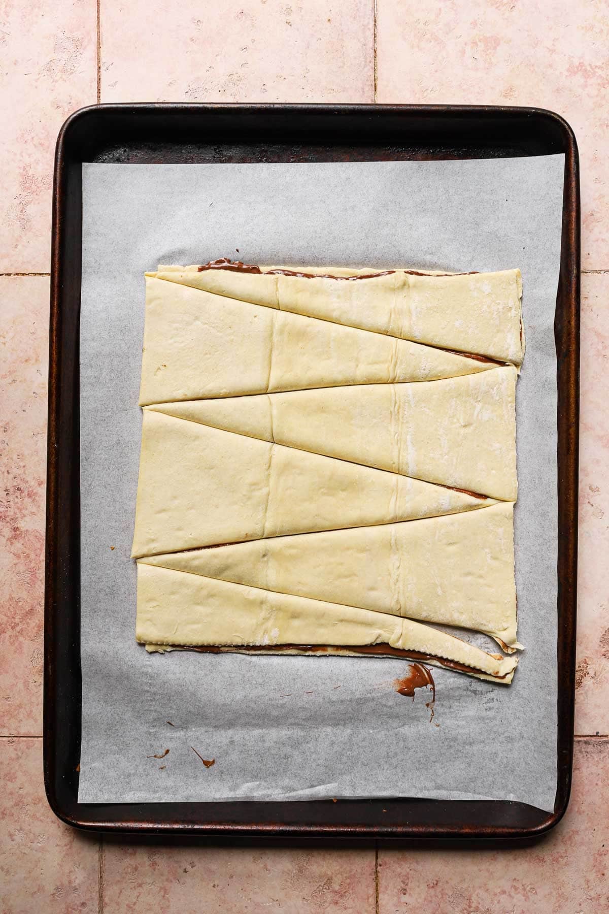 A baking sheet lined with parchment paper and topped with triangle dough.