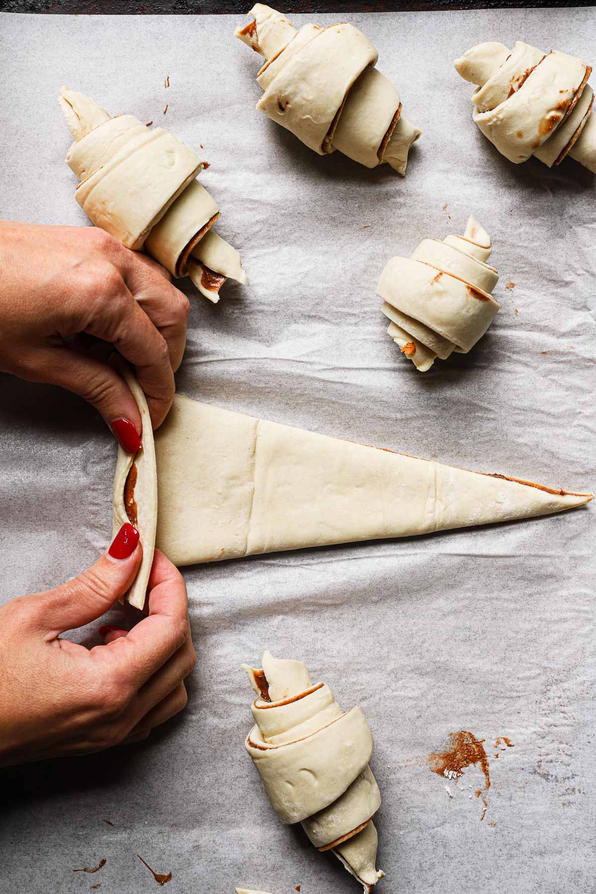 A hand rolling a triangle dough.