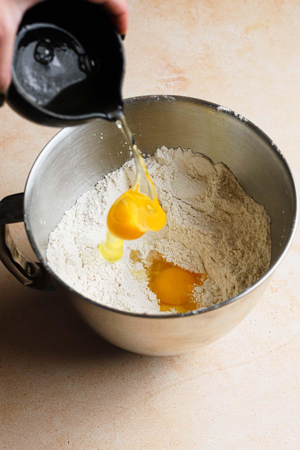 Adding eggs to flour in a mixing bowl.