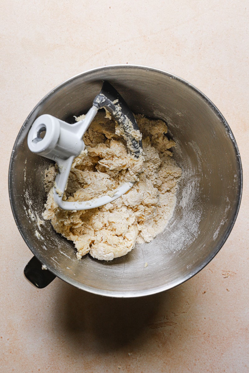 a mixer bowl with a shaggy flour mass and the paddle attachment.
