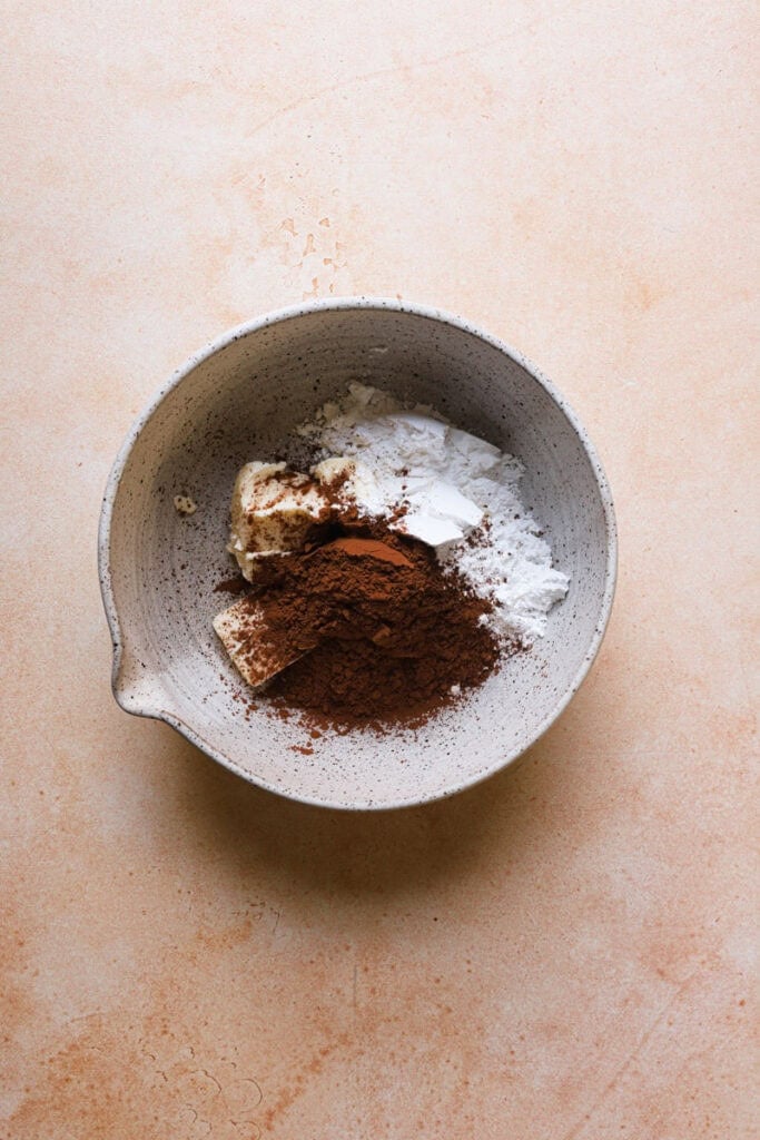 A mixing bowl with butter, powdered sugar and cocoa powder.