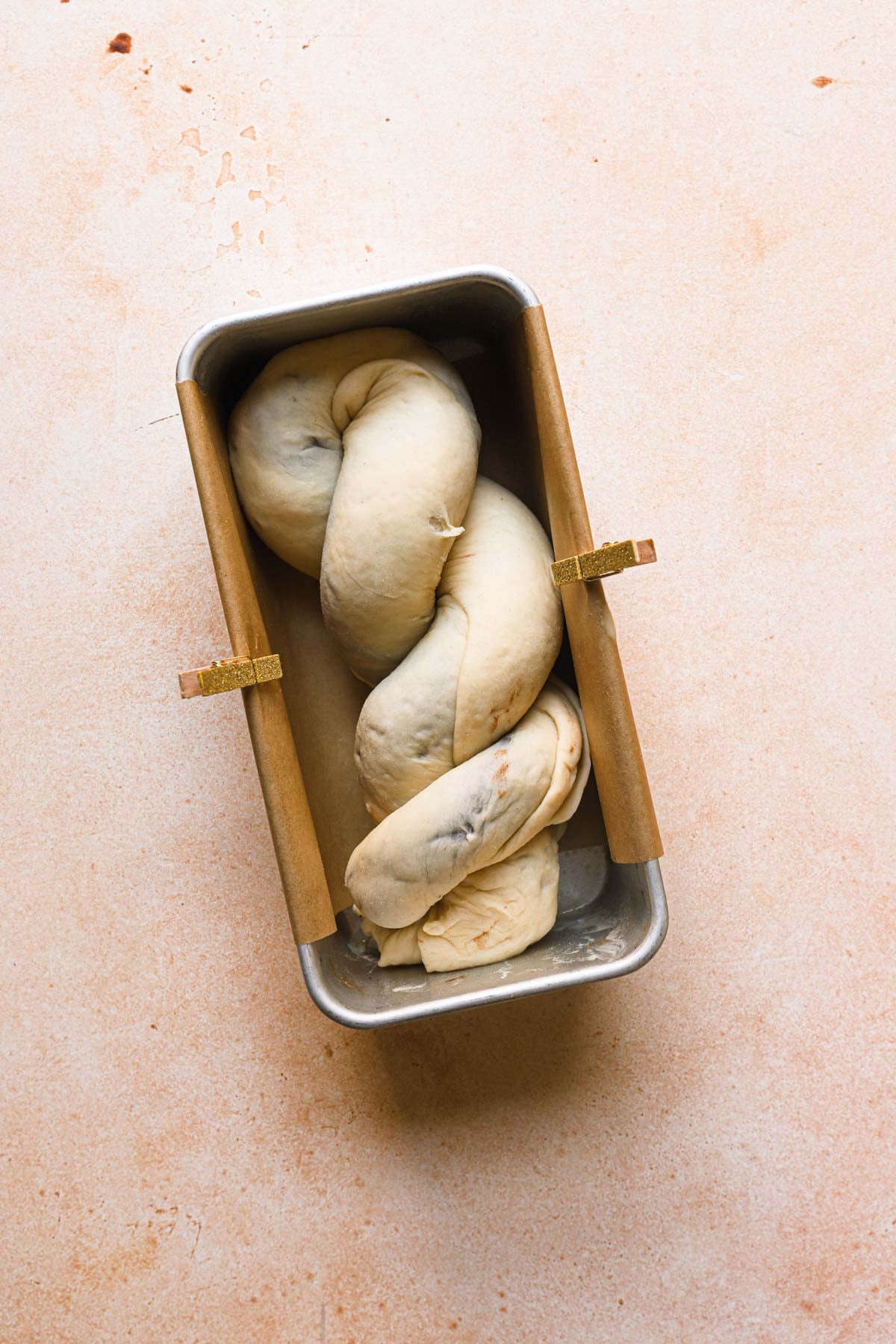Twisted dough in a loaf pan lined with parchment paper.