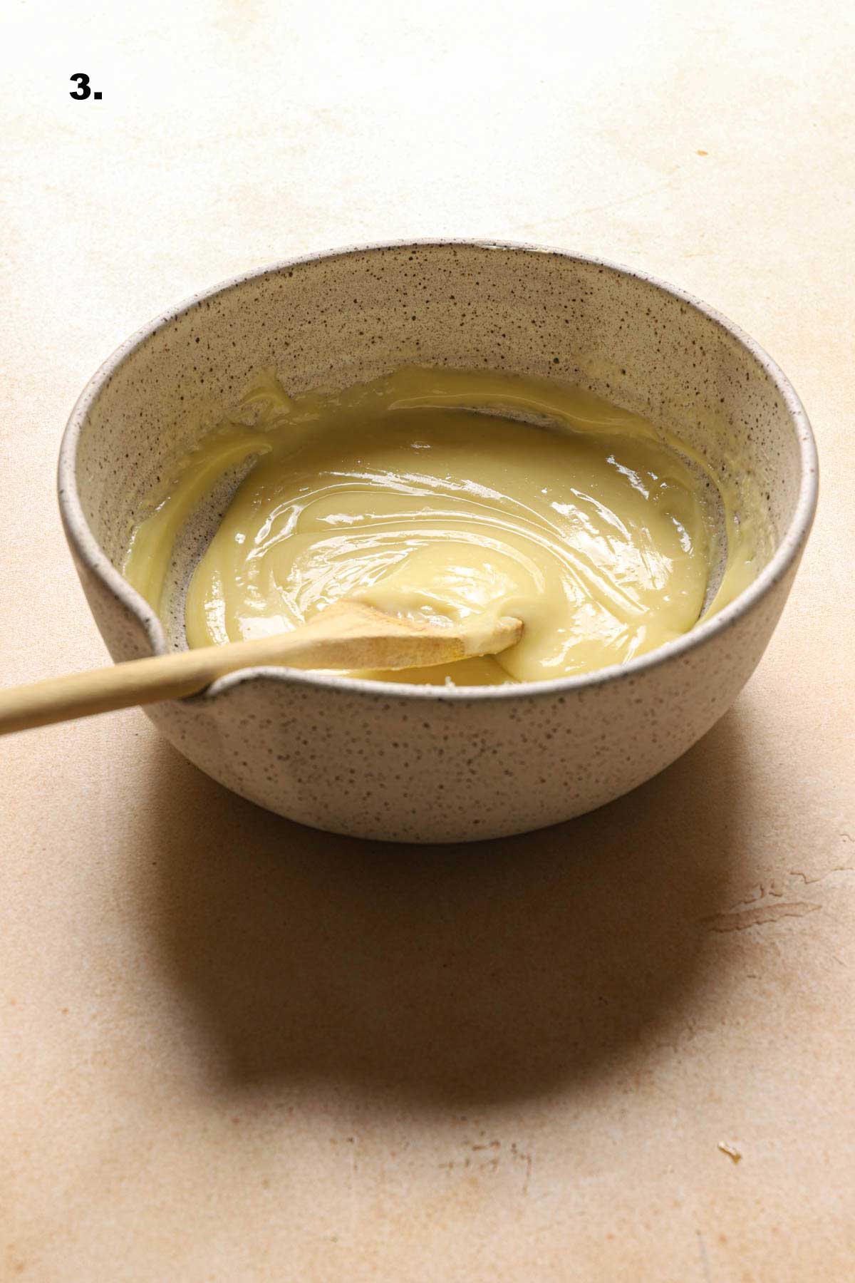 smooth ganache in a bowl with a wooden spoon