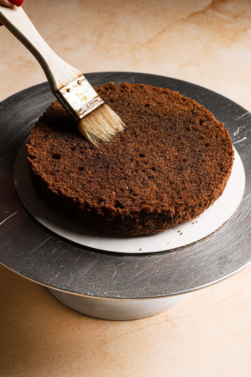a pastry brush soaking chocolate cake