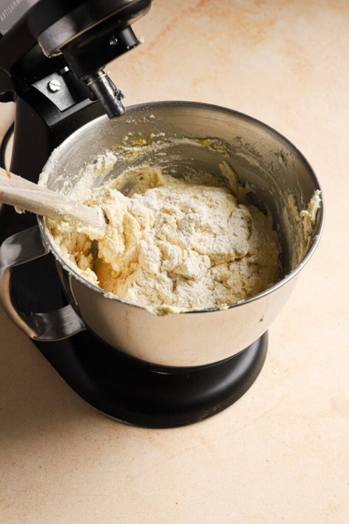 A stand mixer with a bowl filled with a cake batter and a rubber spatual in the batter.